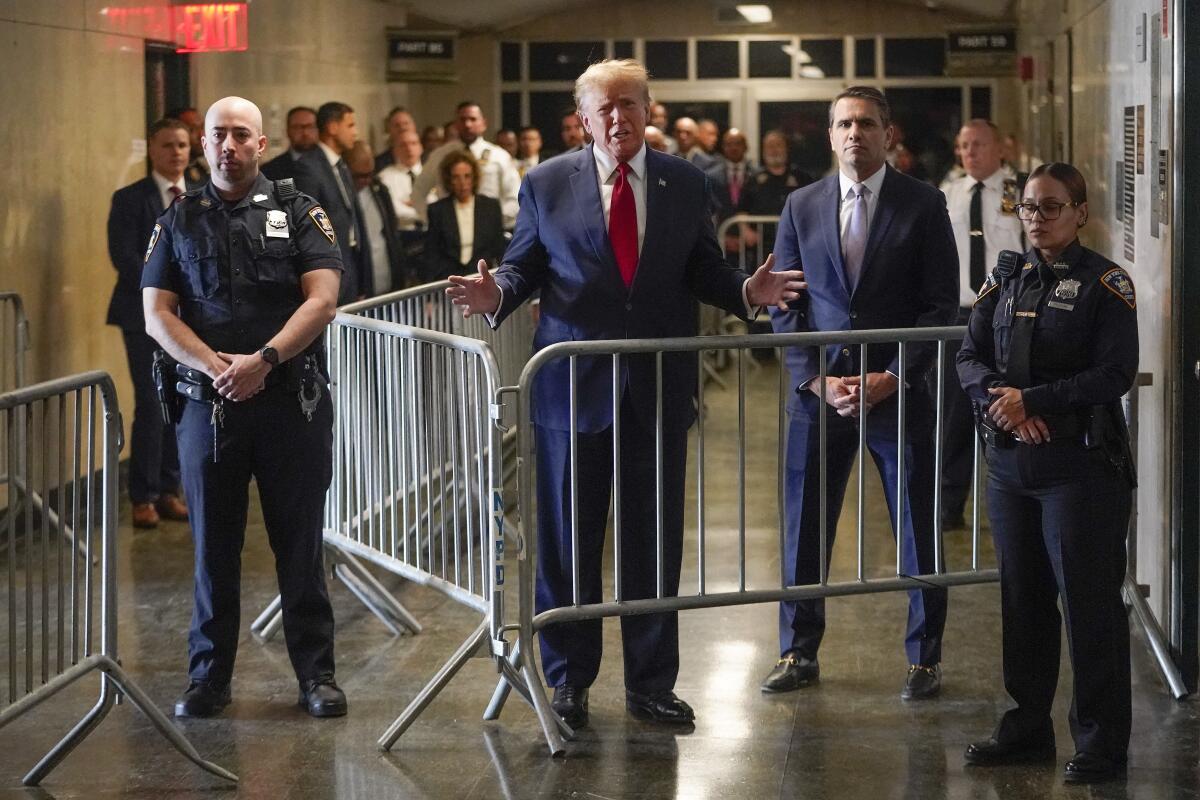 Donald Trump speaking from behind a barrier in a court hallway