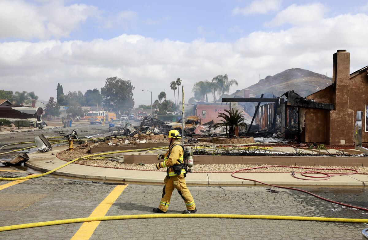 A firefighter is by the scene where a plane crashed and destroyed a home.