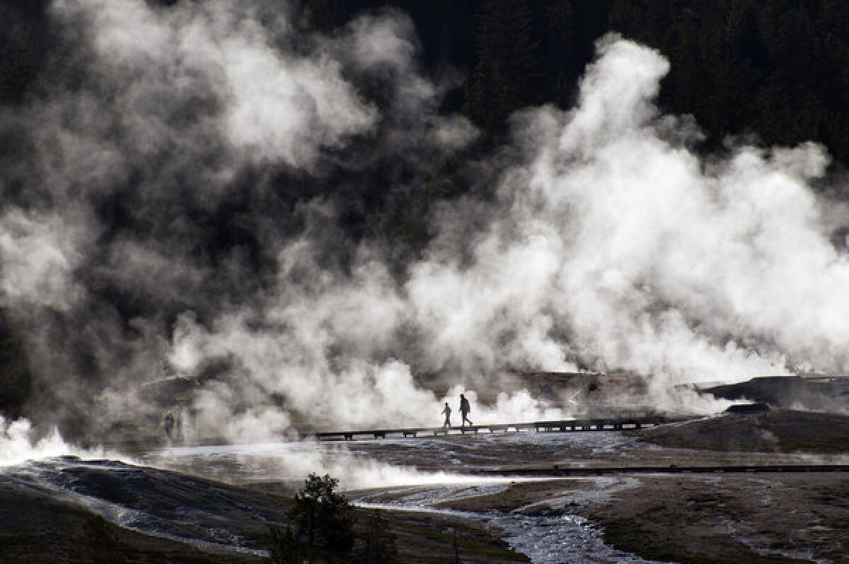 Visitors walk along boardwalks near the Old Faithful geyser in Yellowstone.