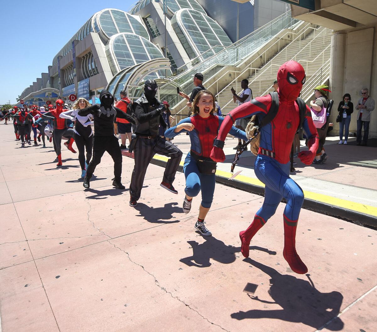 People wearing Spider-Man costumes dance in front of the San Diego Convention Center for a YouTube video.