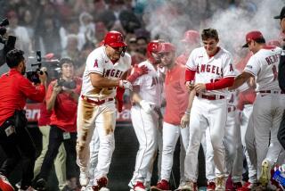 ANHEIM, CA - JUNE 26, 2023: Angels teammates swarm center fielder Mike Trout (27), left, and spray him with powder after he scored the winning run on a wild pitch by Chicago White Sox relief pitcher Aaron Bummer (39) in the ninth inning at Angel Stadium on June 26, 2023 in Anaheim, California. (Gina Ferazzi / Los Angeles Times)