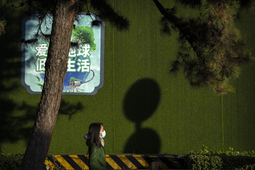 Una mujer, con mascarilla para protegerse del COVID-19 camina por una calle en Beijing, China,
