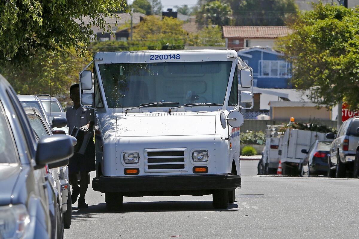 A postal service worker squeezes between his mail truck and parked vehicles along Queens Lane in the Oak View neighborhood.