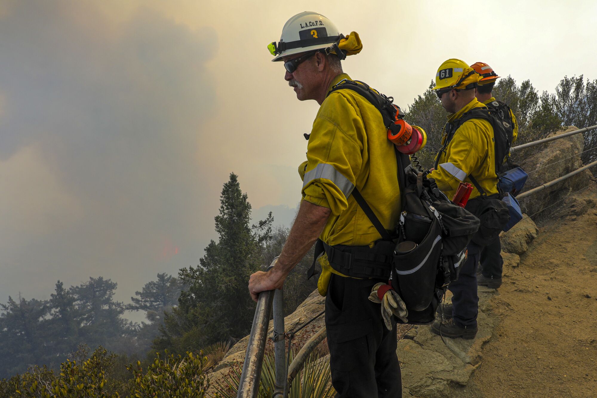 Firefighters stand lookout as the Bobcat fire burns in a canyon near Mt. Wilson Observatory.
