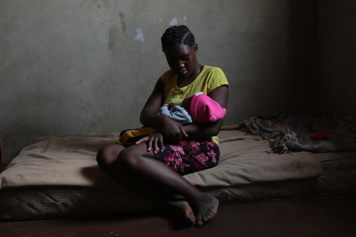 Virginia Mavhunga, de 13 años, sostiene en su brazos a su bebé en su casa de Murehwa (Zimbabue)