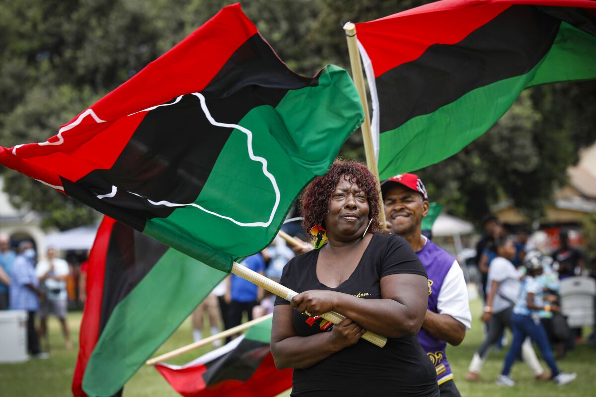 a woman waves a red, black and green flag with a white outline of the African continent on it