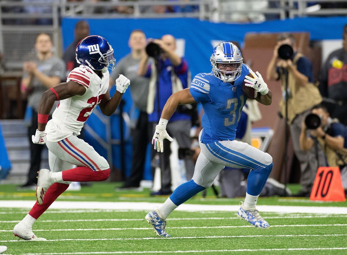 Detroit Lions running back Ty Johnson, right, runs for a first down in front of New York Giants cornerback Deandre Baker during the Lions' win Sunday.