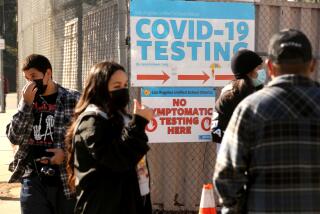 EL SERENO, CA - JANUARY 4, 2022 - - A Health Site Support worker, second from left, directs LAUSD students and staff who wait in line for a COVID-19 test at a walk-up site at the El Sereno Middle School in the El Sereno neighborhood in Los Angeles on January 4, 2022. Students were accompanied by their parents. The Los Angeles school district has ordered coronavirus tests for all students and staff before they return from winter break next week as a new period of high anxiety takes hold among parents and educators amid the explosive surge of the Omicron variant. (Genaro Molina / Los Angeles Times)