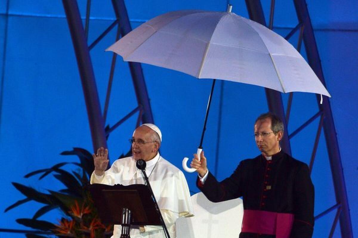 Pope Francis addresses a World Youth Day welcoming ceremony shielded from rain at Rio de Janeiro's Copacabana beach on Thursday.