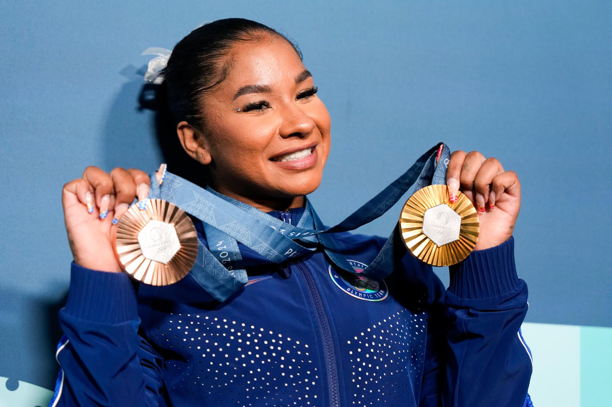 U.S. gymnast Jordan Chiles holds up a bronze and gold medal at the Paris Olympics