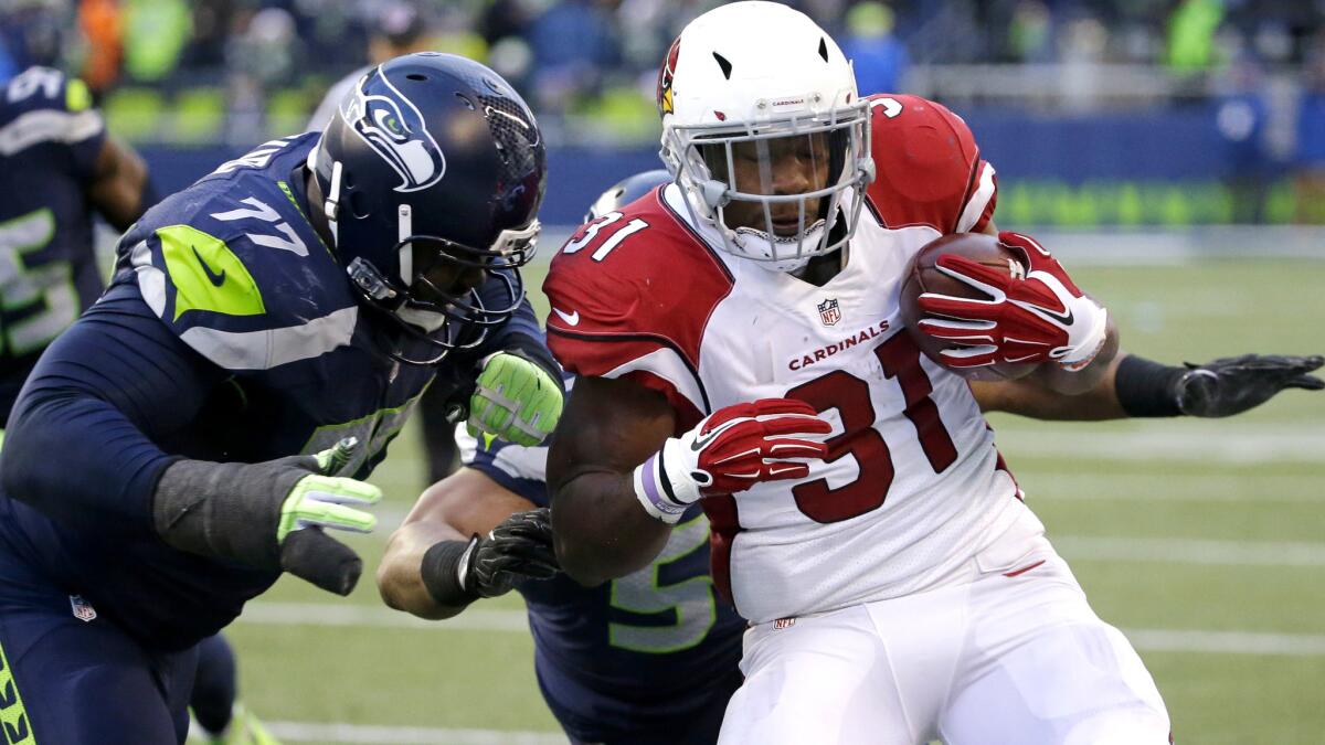 Cardinals running back David Johnson is brought down by Seahawks defenders Ahtyba Rubin, left, and Bobby Wagner after a gain during the second half Saturday.