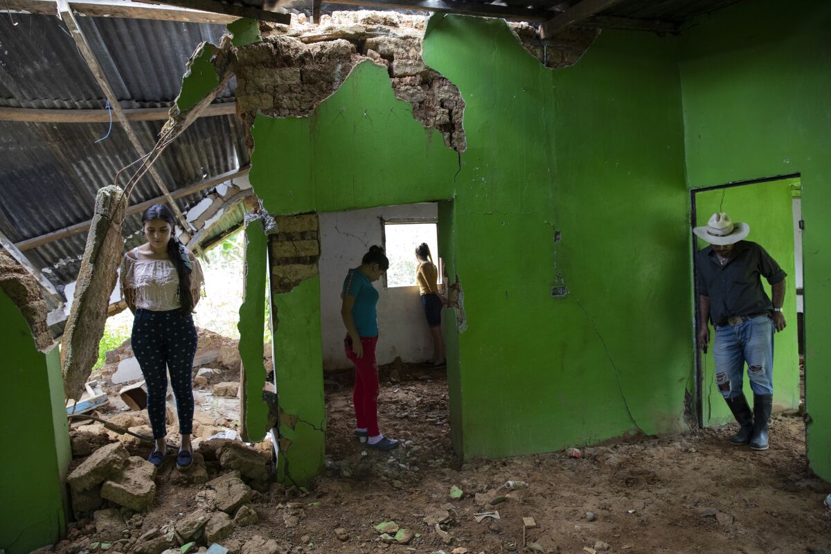 From left, Marian Castron, 23; Maria Castron, 25; Jenny Castron, 19, and Omar Castron, 50, visit their home devastated by a landslide triggered by hurricanes Eta and Iota in the village of La Reina, Honduras, Friday, June 25, 2021. "We plan to return, but it will be impossible," says Omar. Home to about 1,000 people, the town in western Honduras was hit by two powerful hurricanes within three weeks, natural disasters made far worse by local deforestation and climate change. (AP Photo/Rodrigo Abd)