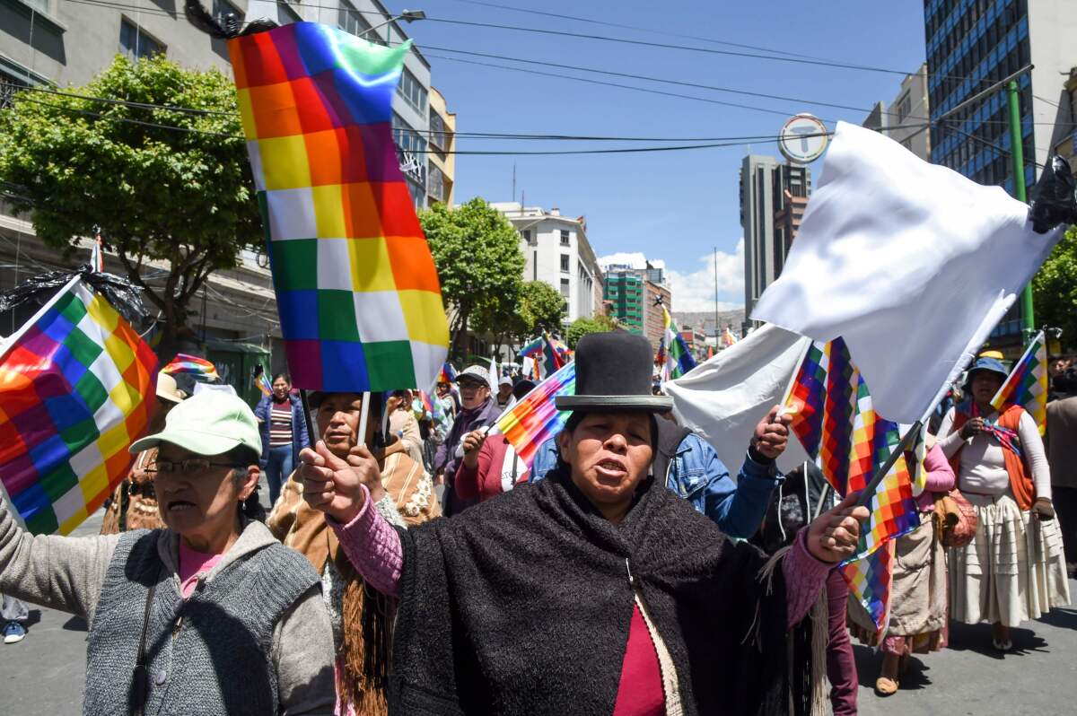 Partidarios del ex presidente boliviano Evo Morales sostienen banderas whipalas, de los pueblos originarios, en La Paz. La presidenta interina de Bolivia afirmó el domingo que convocará a nuevas elecciones pronto, mientras el país lucha con violentos disturbios una semana después de la renuncia de Evo Morales. (AIZAR RALDES / AFP / Getty Images)