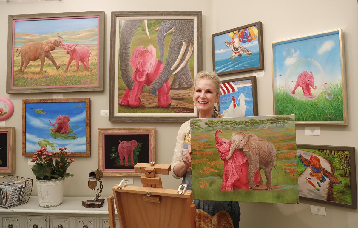 Wildlife artist Laura Curtin stands with her trademark pink elephants.