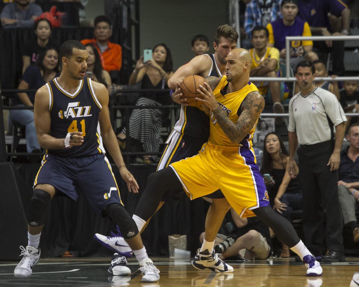 Lakers center Robert Sacre struggles for the ball against Utah center Jeff Withey (24) during overtime of a preseason game against the Jazz on Oct. 6.