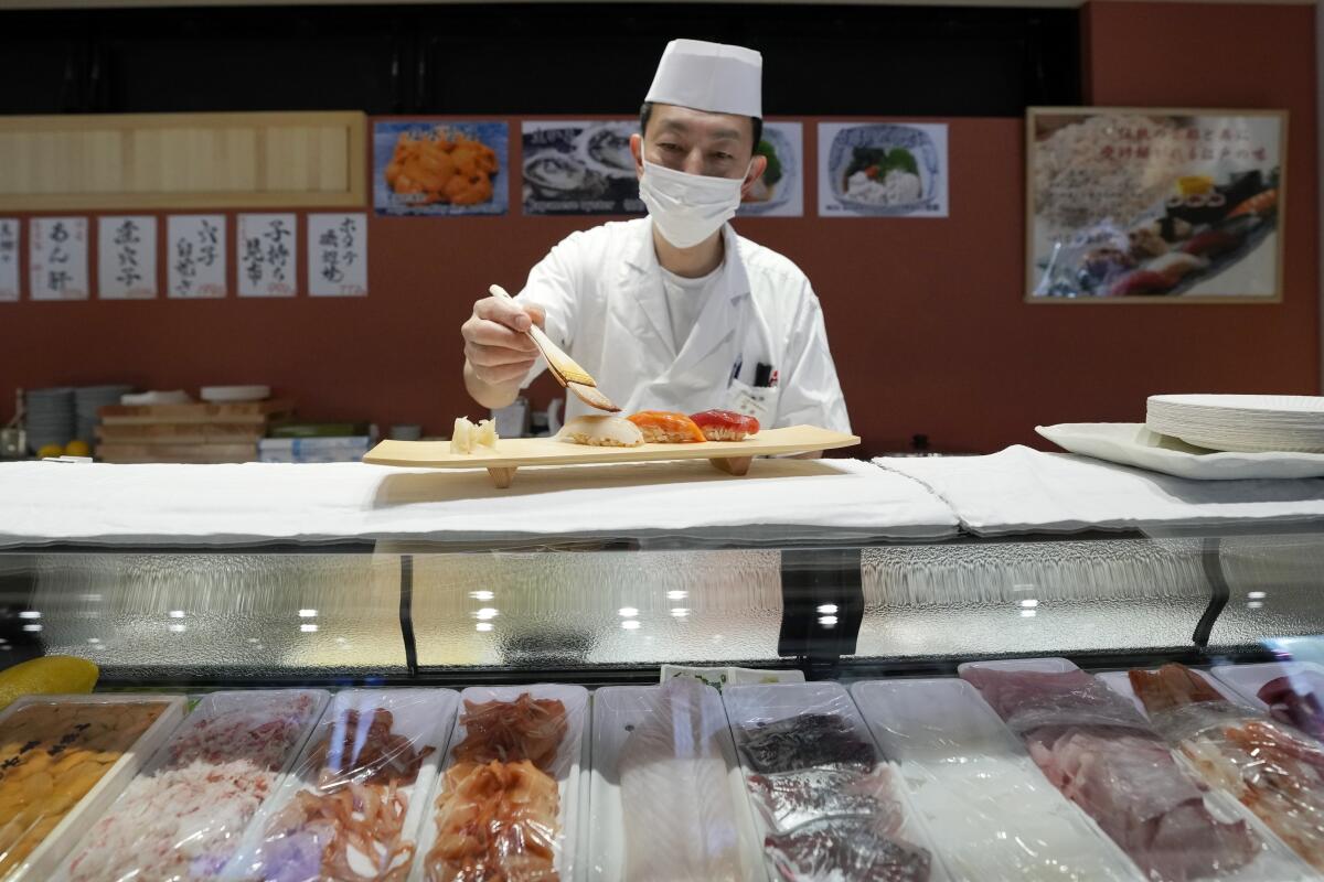 A sushi chef works at a counter.