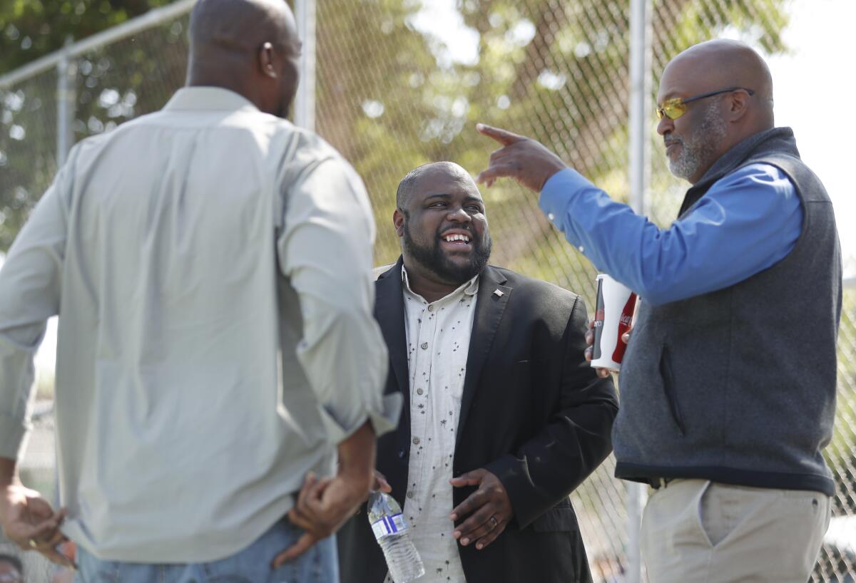 Three men stand outside talking among themselves.