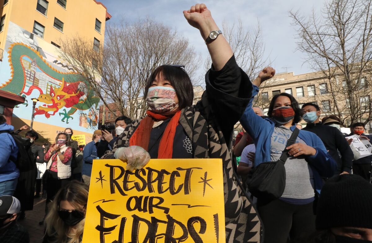 An Asian American woman holds up a sign that says "Respect our elders!"