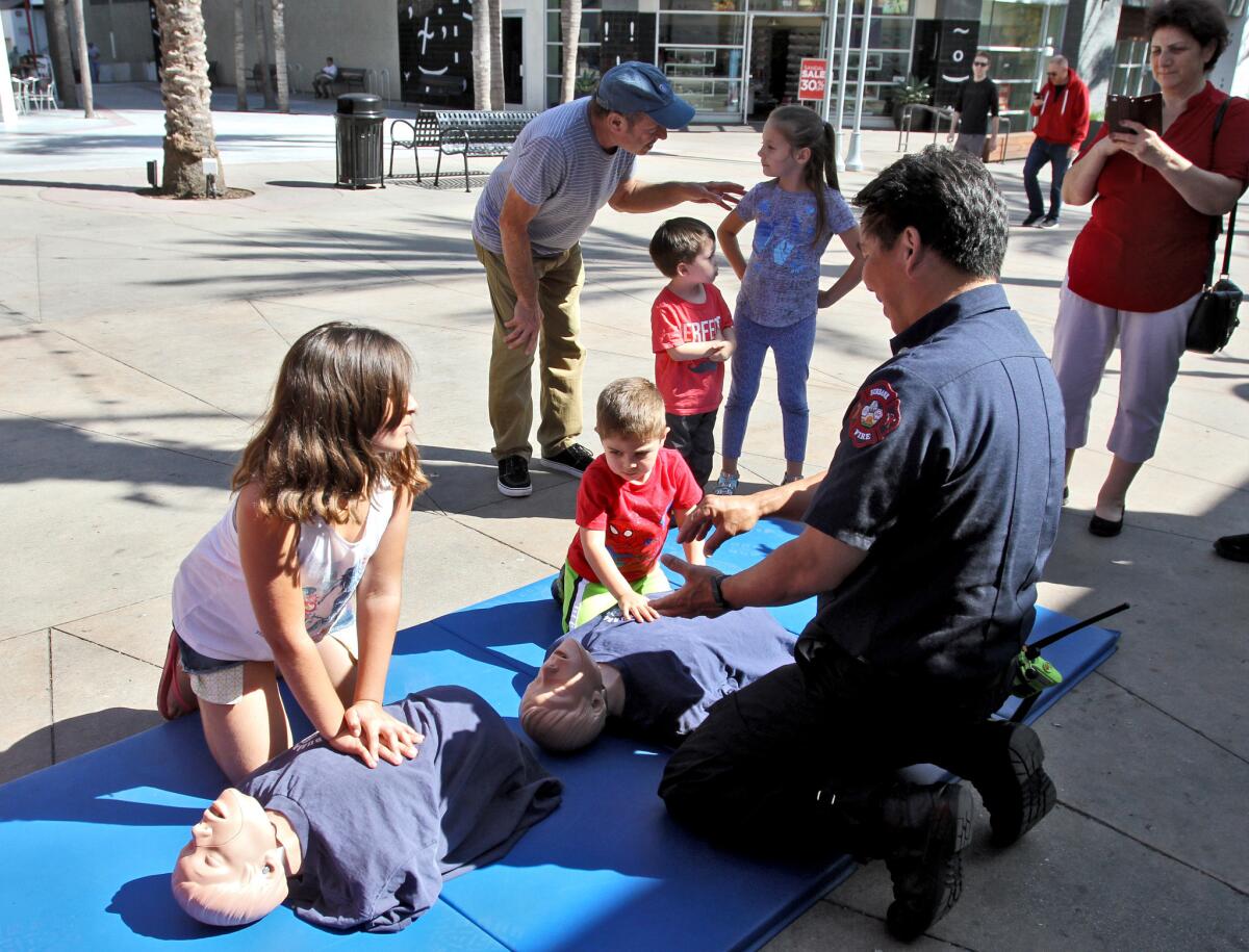 Burbank Fire Department Captain Darryl Isozaki shows Emma Petrosyan, left, and her brother Henry Petrosyan, right, how to properly perform compressions during the Burbank sidewalk CPR at Paseo Del Fuego at Palm Ave. and San Fernando Road in Burbank on Thursday, June 2, 2016.