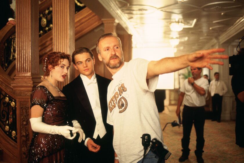 A movie director points while two actors are dressed in formal clothing