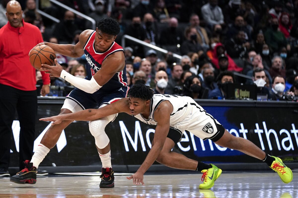Brooklyn Nets guard Cam Thomas, right, dives for the ball held by Washington Wizards forward Rui Hachimura during the second half of an NBA basketball game Thursday, Feb. 10, 2022, in Washington. The Wizards won 113-112. (AP Photo/Evan Vucci)