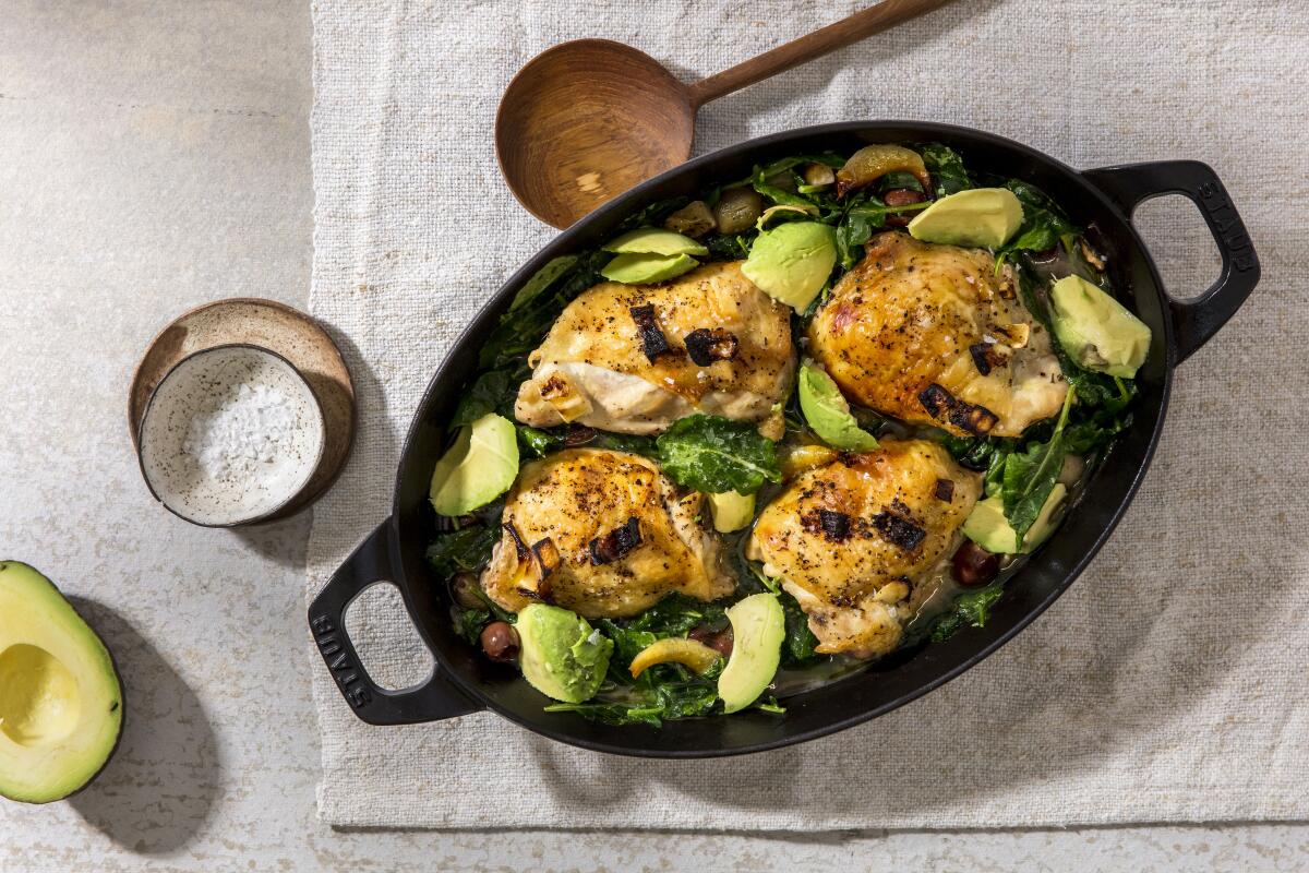 Olive brine-braised chicken thighs in a black oval dish.