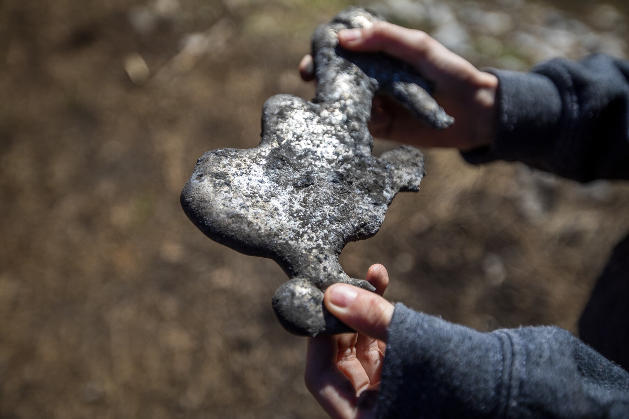 Pandora Hammonds, 9, holds a piece of melted aluminum on their family's property in Grizzly Flats.