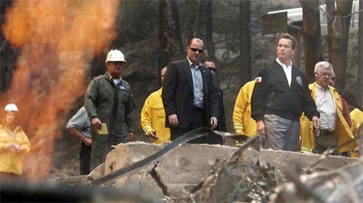 OMNIPRESENT: Gov. Arnold Schwarzenegger tours the scorched area along Brentwood Drive in Lake Arrowhead on Tuesday. He has been on nearly nonstop visits to fire-afflicted areas since Monday.