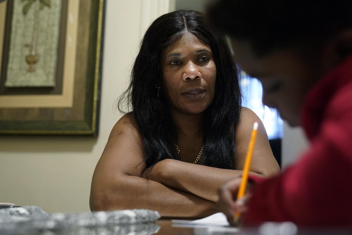 A woman looking at her son as he does homework with a pencil