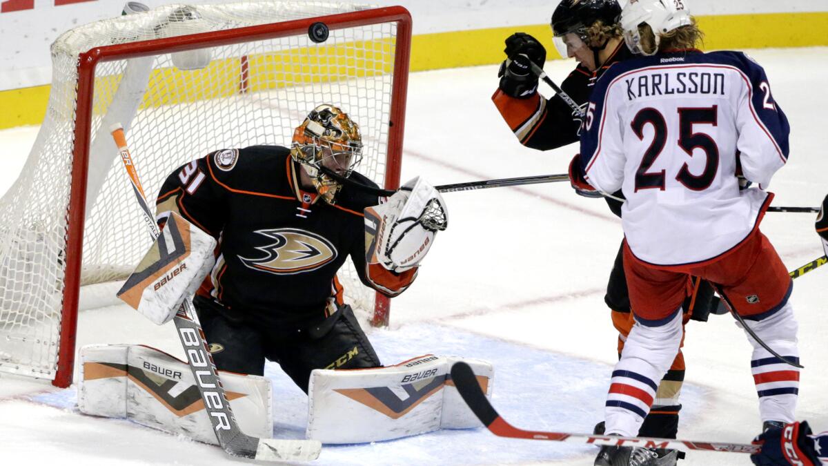 Ducks goalie Frederik Andersen looks to his glove for the puck, which sailed over his head as defenseman Hampus Lindholm and Blue Jackets center William Karlsson batte for position Friday night.