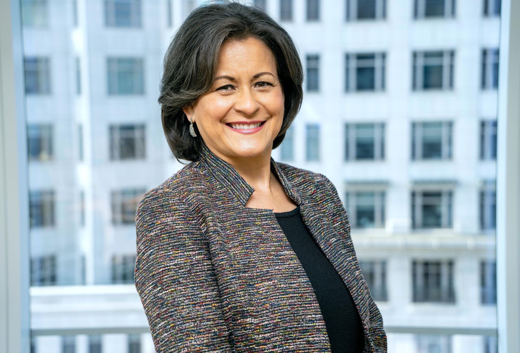 A woman with dark hair smiles.