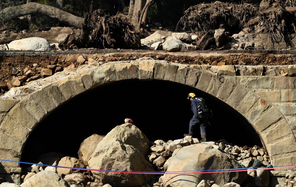 Tim O'Donnell, a member of the L.A. County Search and Rescue team, searches under Ashley Road along the East Cold Springs Creek in Montecito after a major storm hit the burn area. (Wally Skalij/Los Angeles Times)