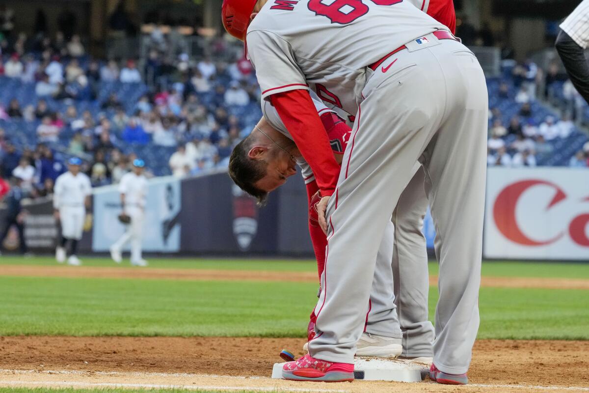 Angels first base coach Damon Mashore checks on Logan O'Hoppe after he was injured during the ninth inning Thursday.