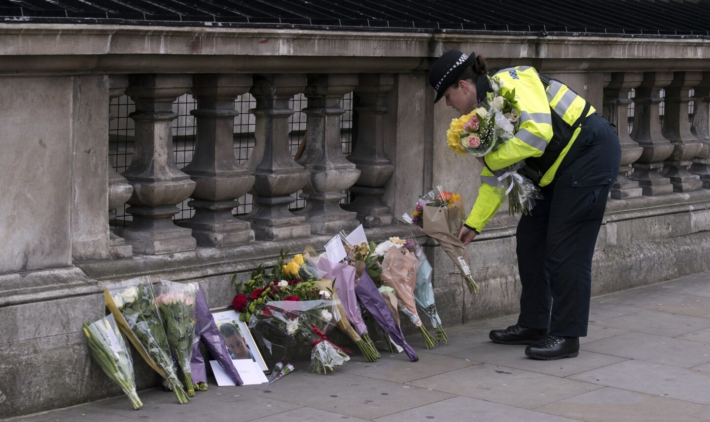 A police officer places flowers from members of the public in London.