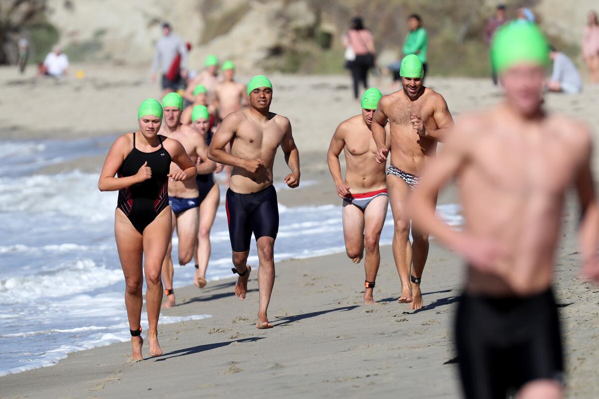 Participants run along the beach during Laguna Beach ocean lifeguard tryouts at Main Beach on Saturday.