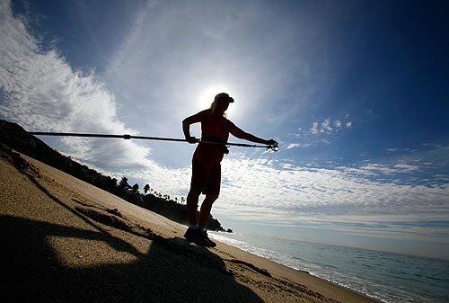 Tami Halle of the Orange County Health Care Agency uses a 10-foot pole to collect water samples at Aliso Beach in Laguna Beach after 580,000 gallons of sewage spilled from a pump station into the ocean early Wednesday.