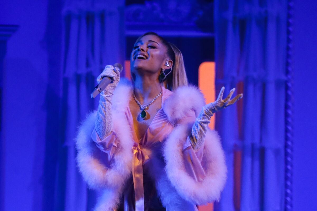 A woman singing into a microphone under purple lighting