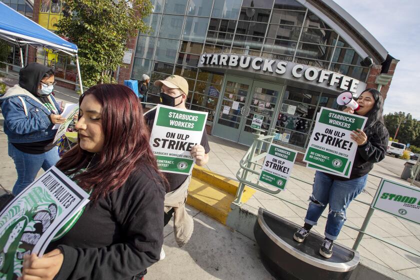 LOS ANGELES CA DECEMBER 16, 2022 - Workers picket outside a Starbucks in downtown Los Angeles. The union organizing Starbucks workers declared a strike at dozens of stores on Friday, Dec. 16, 2022, the latest escalation in its campaign to secure a labor contract. (Brian van Der Brug / Los Angeles Times)
