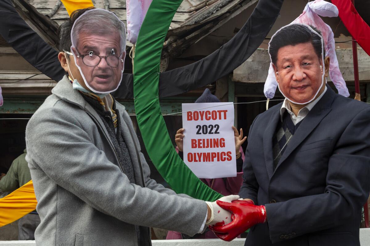 Activists wearing masks of IOC President Thomas Bach and China President Xi Jinping shakes hands with red on their gloves.
