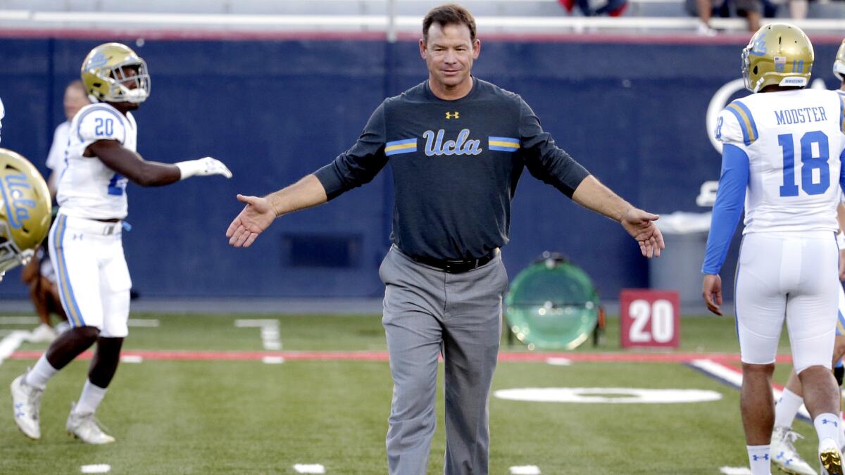 Coach Jim Mora slaps hands with his UCLA players before their game against Arizona.