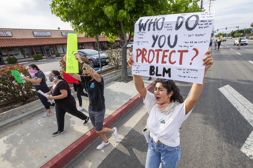 Nina Veyseh, 19, from Laguna Hills, carries a sign along Fairview Road during a a peaceful demonstration on Tuesday, June 2.