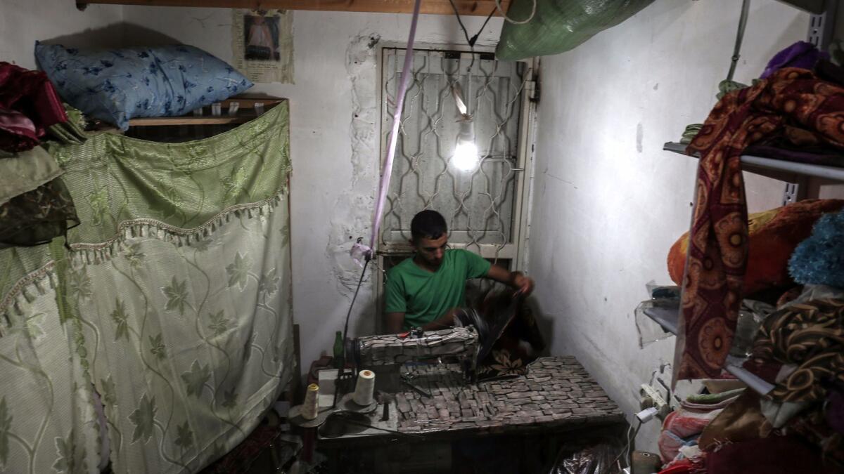 A Palestinian tailor works at a sewing workshop July 11 during the few hours of electricity residents of the Gaza Strip receive per day.