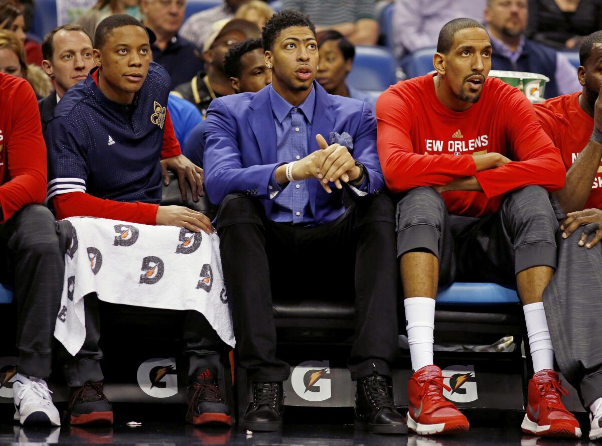 Pelicans forward Anthony Davis, center, sits on the bench with teammates Alexis Ajinca, right, and Tim Frazier, left, in the first half.