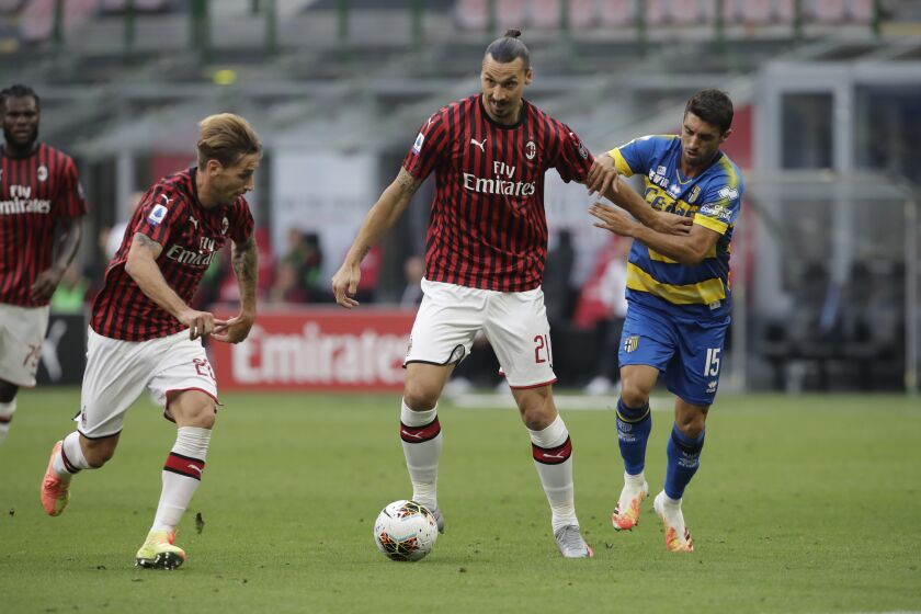 AC Milan's Zlatan Ibrahimovic, centre, fights for the ball with Parma's Gaston Brugman, right, during a Serie A soccer match between AC Milan and Parma, at the San Siro stadium in Milan, Italy, Wednesday, July 15, 2020. (AP Photo/Luca Bruno)