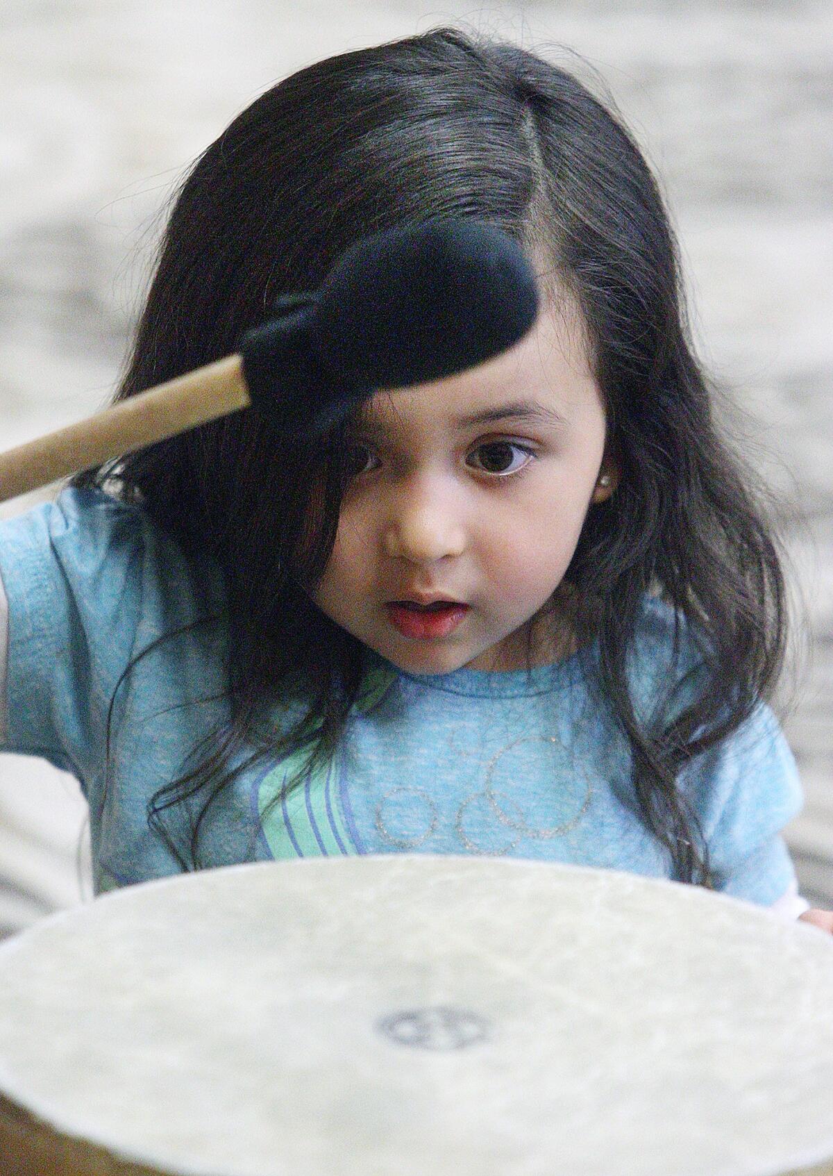 Olivia Osorio, 3, of Burbank, plays a drum with a mallet during family night at the Buena Vista Branch Library in Burbank on Thursday, March 31, 2016.