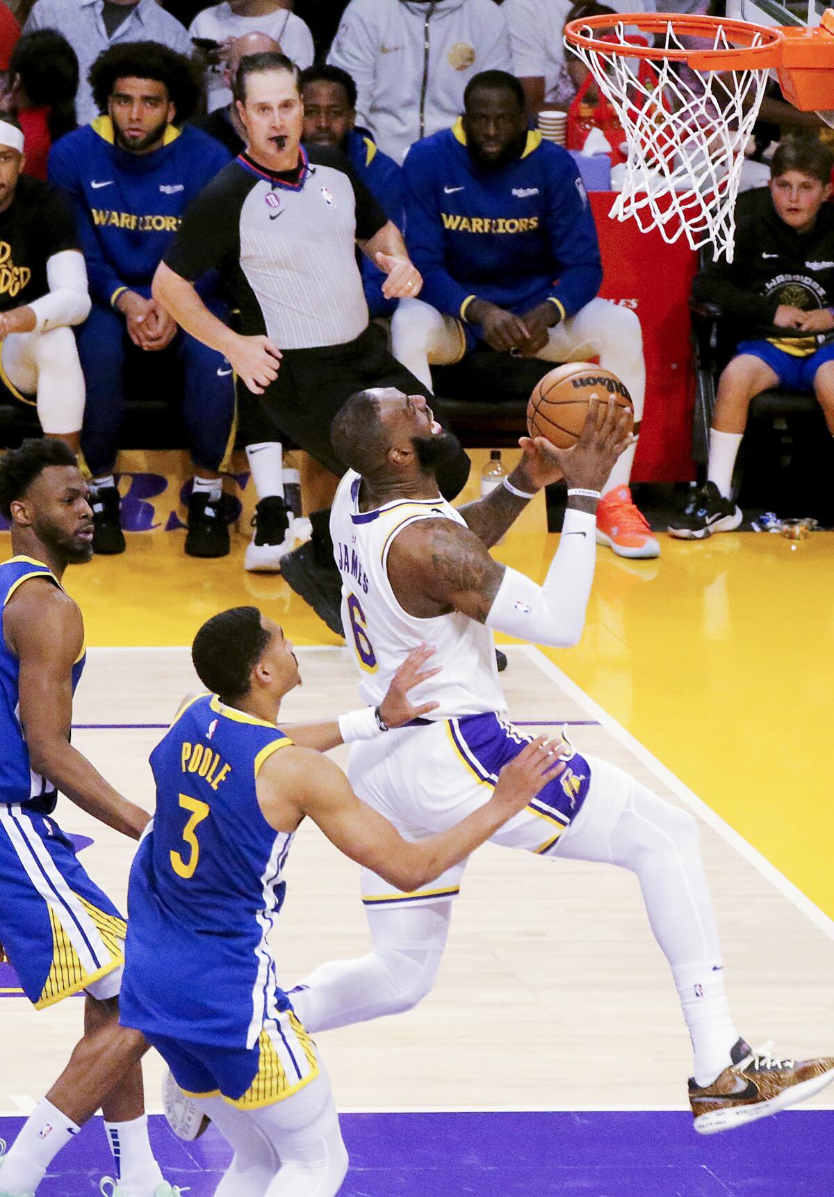 Lakers forward LeBron James, right, drives past Warriors forward Andrew Wiggins for a layup.