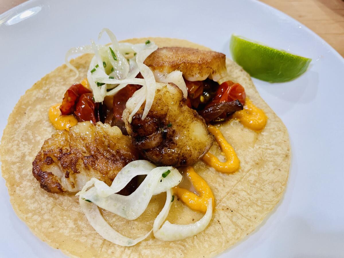 A scallop taco with chile sauce, fennel, caramelized onions and cherry tomatoes on a corn tortilla