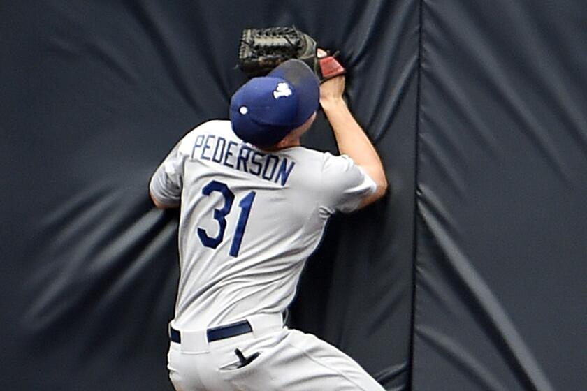 Dodgers center fielder Joc Pederson crashes into the wall moments after making an over-the-shoulder catch on the run on a ball hit by Padres outfielder Justin Upton in the ninth inning Sunday.