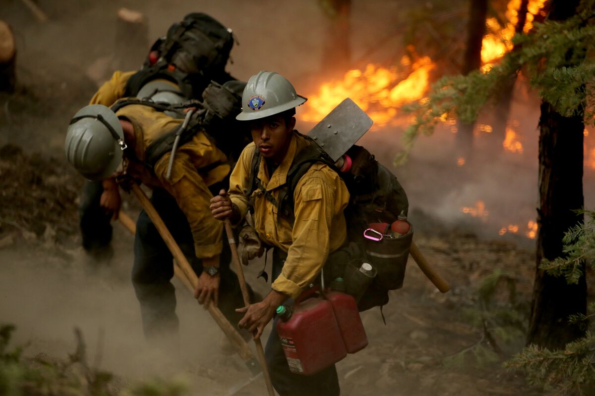 A fire crew at work with flames in the near background.