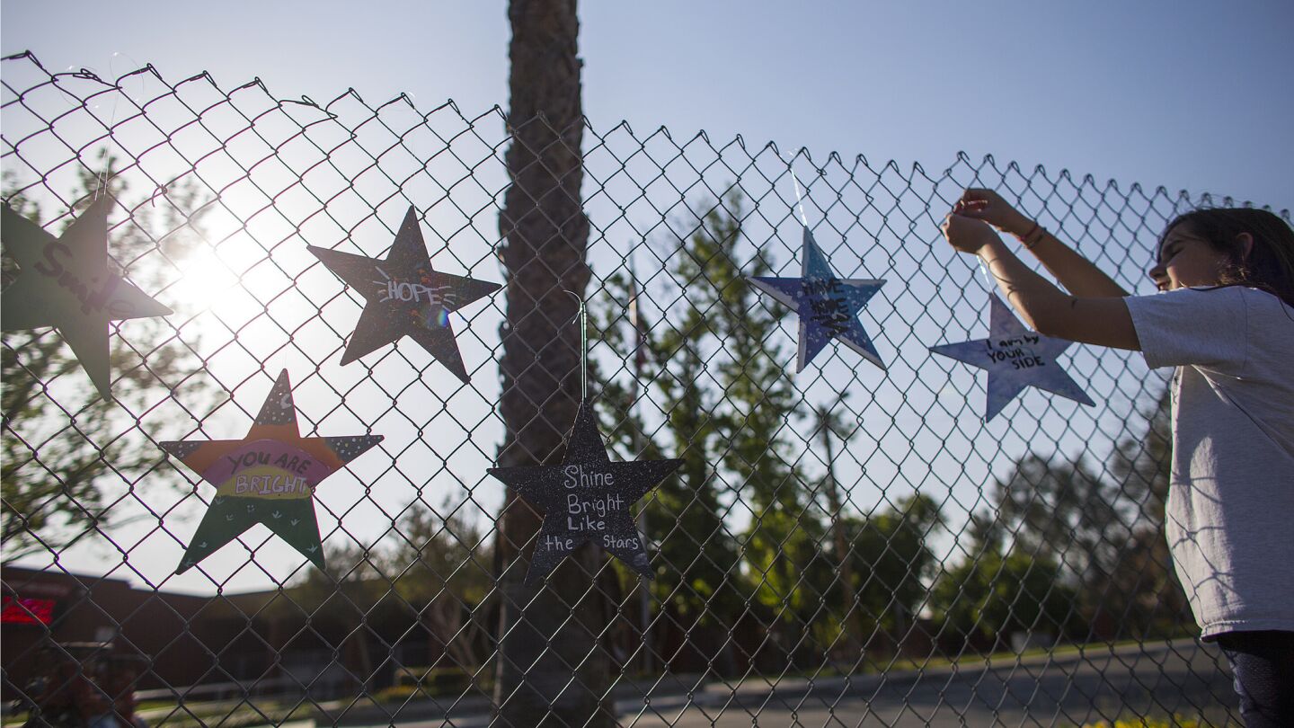 Ellie Paez places homemade "Stars of Hope" along the fence at North Park Elementary School.